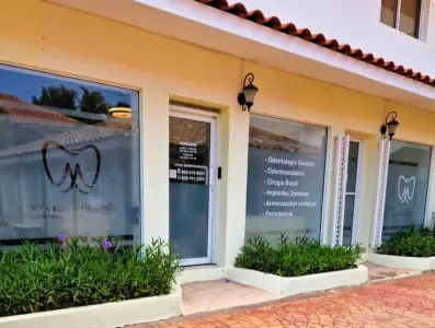الواجهة الخارجية لعيادة Punta Cana Family Dental Clinic مع قائمة خدمات الأسنان على النوافذ