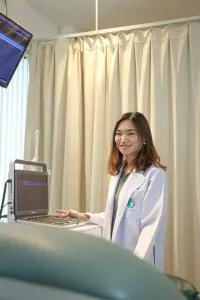 Doctora en Genesis Fertility Center con equipo de ultrasonido en sala de exámenes