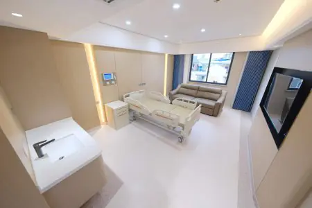 Habitación de paciente en Uni-asia Cancer Hospital con cama moderna y sofá