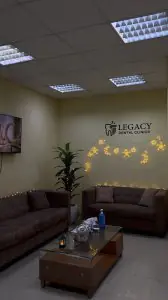 منطقة انتظار الاستقبال في Legacy Dental Clinics مع أرائك وأضواء زخرفية