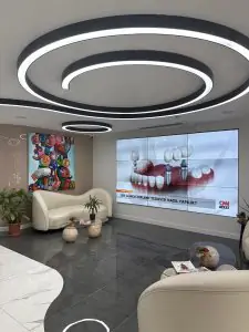 منطقة انتظار حديثة في EB Dental Clinic مع مقاعد أنيقة وشاشة عرض لزراعة الأسنان