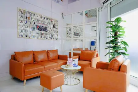 منطقة انتظار في Saigon Center Dental Clinic مع أرائك برتقالية حديثة وديكور