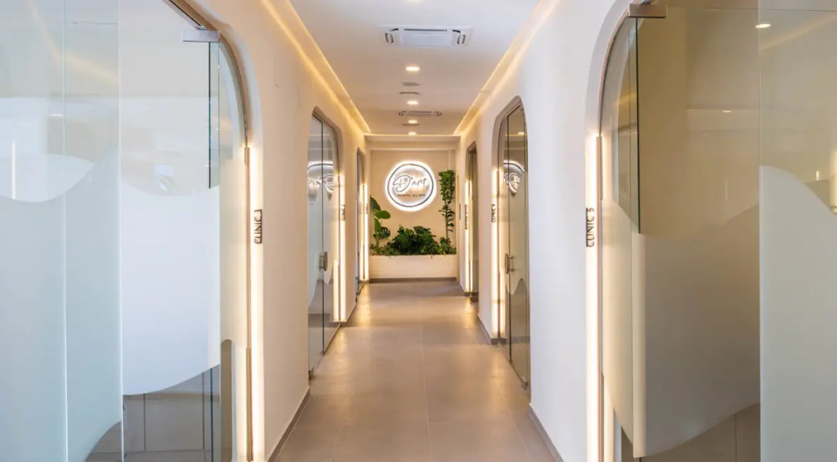 Couloir moderne à la D’Art Dental Clinic avec portes en verre et éclairage