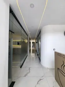 ممر حديث بجدران زجاجية وأرضية رخامية في عيادة Taki Dent