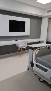 غرفة مريض في عيادة MEDICTERREAN® بسرير طبي وتلفزيون وأثاث حديث
