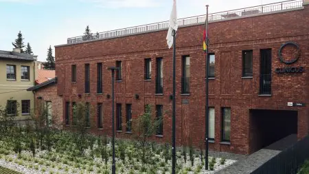 الواجهة الخارجية لعيادة Clinicus Klaipeda بواجهة من الطوب وحديقة منسقة