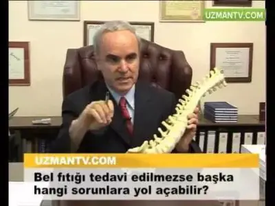 Doctor en Doç. Dr. Ahmet Yıldızhan Muayenehanesi explicando modelo de columna en oficina