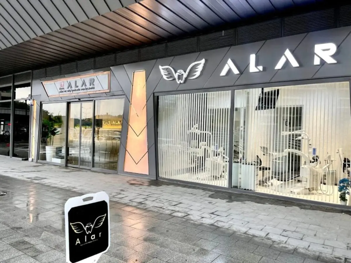 Fachada de la clínica Alar Dent con sillones dentales visibles a través de las ventanas