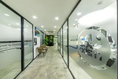 Pasillo moderno con paredes de vidrio en 360 Dental Clinic, sillones dentales visibles en las salas