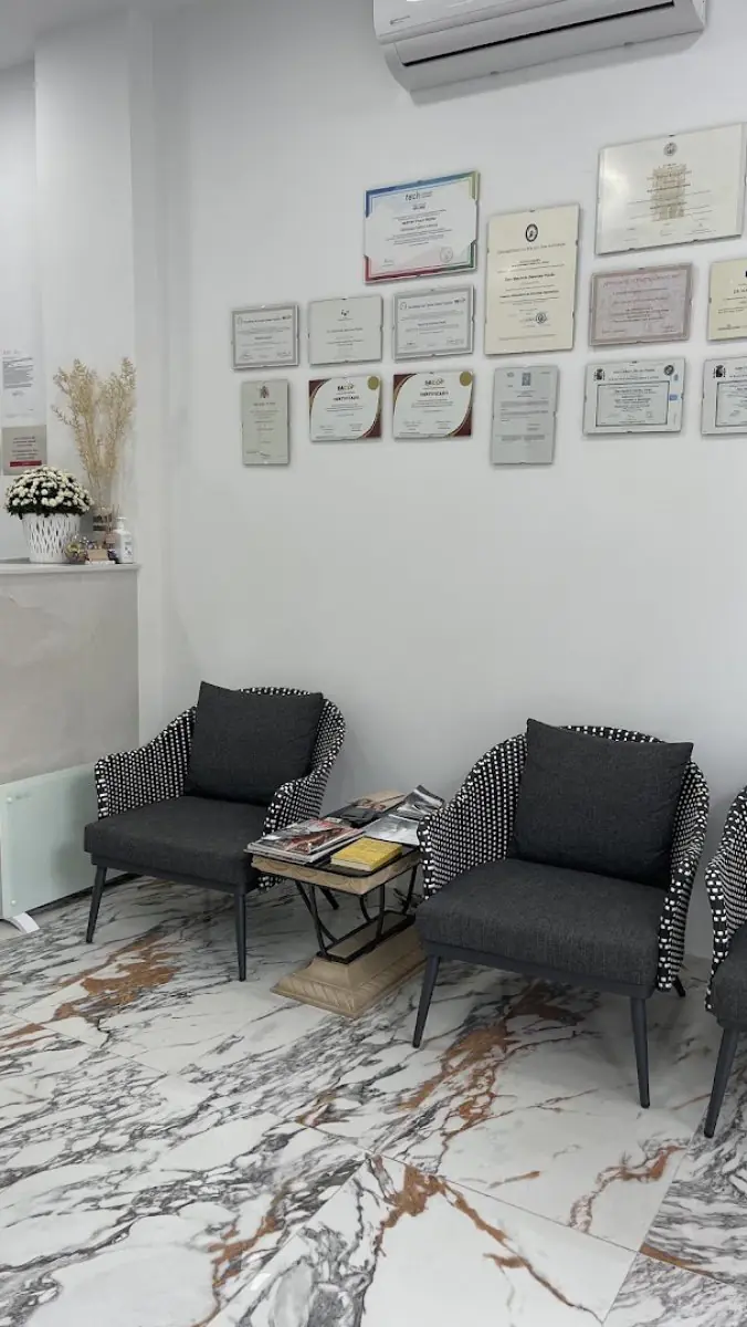 Wartebereich der Facialia Klinik mit modernen Stühlen, Marmorboden und Zertifikaten an der Wand