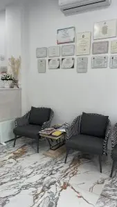 منطقة انتظار عيادة Facialia بكراسي حديثة وأرضية رخامية وشهادات على الجدار