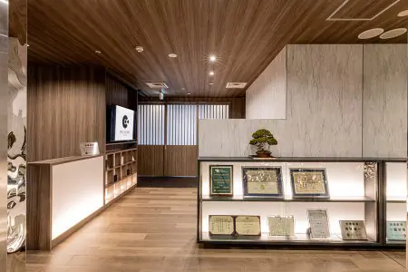 Recepción en CELL GRAND CLINIC con interior moderno de madera y vitrina de premios