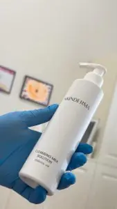 محلول حليب منظف SKINDERMA في يد مرتدية قفاز داخل عيادة
