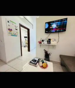 منطقة انتظار عيادة AllDental مع تلفاز ومجلات وإطلالة على غرفة علاج الأسنان