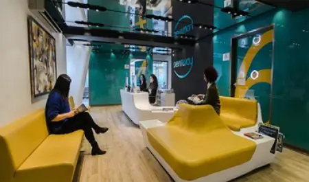 Recepción y sala de espera en Dentway Dental Clinic con asientos amarillos modernos