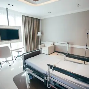 غرفة مرضى في Hermes Clinics بسرير طبي وتلفاز وأثاث حديث
