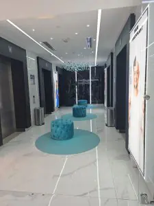 Área de espera moderna en Paradise Polyclinic con asientos azules y suelos de mármol