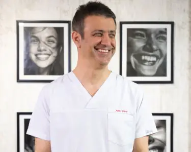 طبيب أسنان يرتدي الزي في عيادة Ader Dent، صور ابتسامات على الجدار