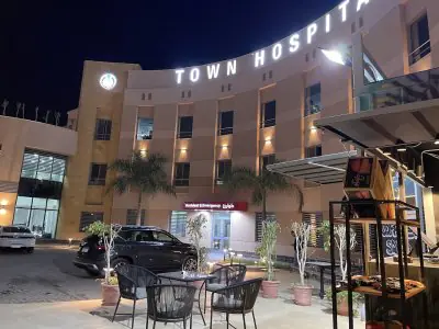 Fachada de Town Hospital de noche con entrada de emergencias y asientos exteriores