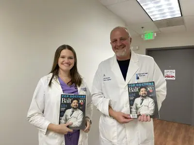 Doctores de Ascension Saint Agnes Bariatric Surgery con revista Top Doctors en pasillo de la clínica