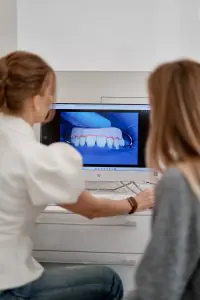استشارة طب الأسنان في DentalDate TMJ Institute مع نموذج أسنان رقمي على الشاشة