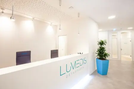 منطقة الاستقبال في عيادة Lumedis Orthopäden بتصميم داخلي أبيض عصري