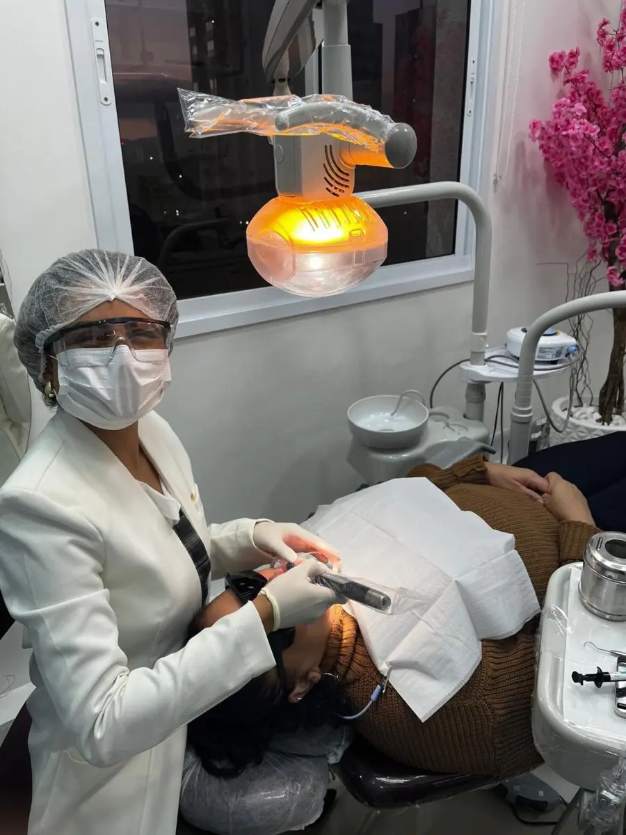 Стоматолог проводит процедуру в кабинете клиники Dr. Cléo Salustiano