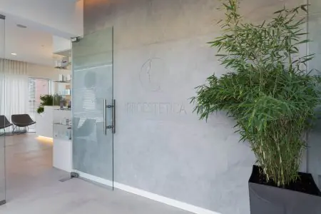 Recepción moderna en PROESTETICA Klinika dr Prager con puerta de vidrio y plantas