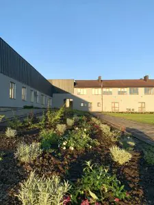 Exterior de la clínica Rea:Medical con jardín paisajístico y edificio moderno