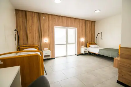 Habitación de pacientes en la clínica Rea:Medical con camas modernas y paredes de madera
