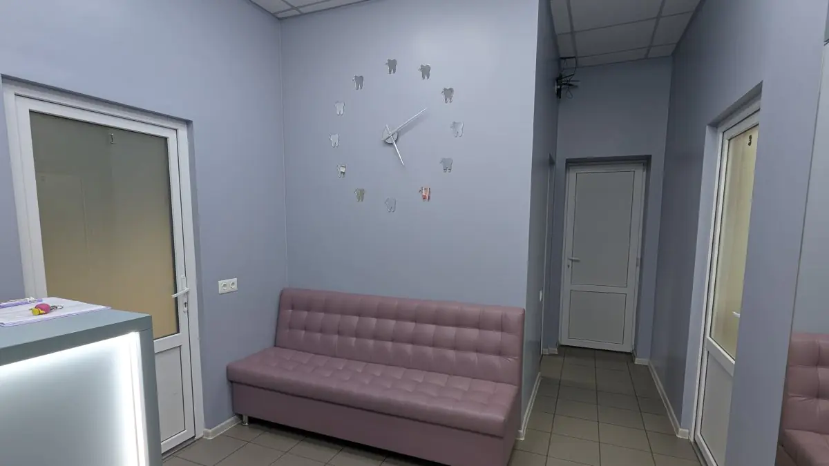 Espace d'attente à Synergy Dental Clinic avec canapé moderne et horloge murale en forme de dent