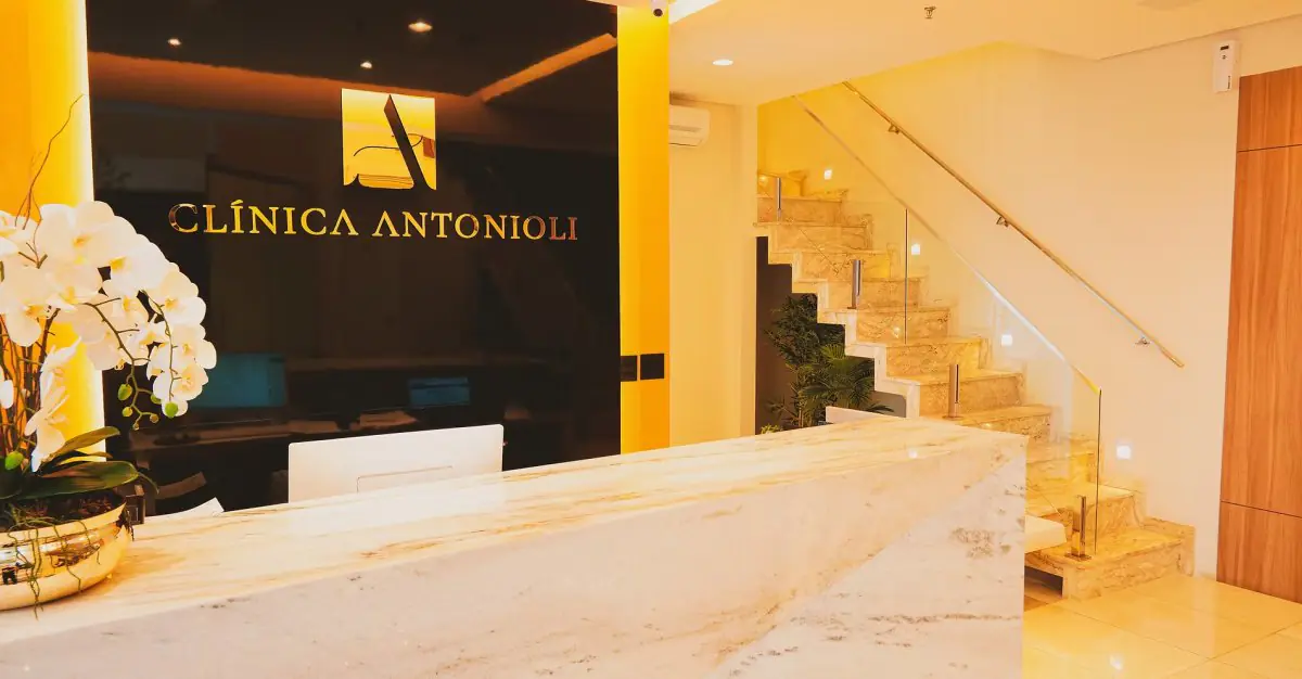 Empfangsbereich der Clínica Antonioli mit Marmortheke und moderner Treppe