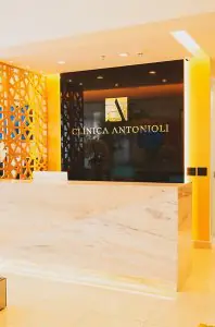 Área de recepción en Clínica Antonioli con mostrador de mármol moderno y decoración luminosa