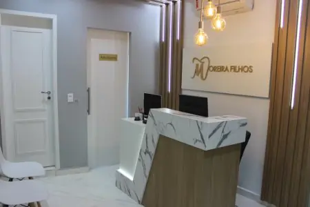 Área de recepción en la clínica Moreira Filhos con mostrador moderno de mármol y asientos