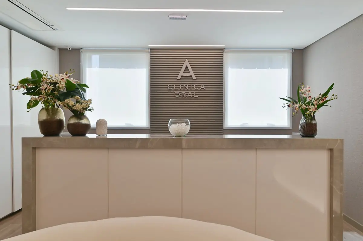 Reception desk at Clinica Oral with modern decor and floral arrangements