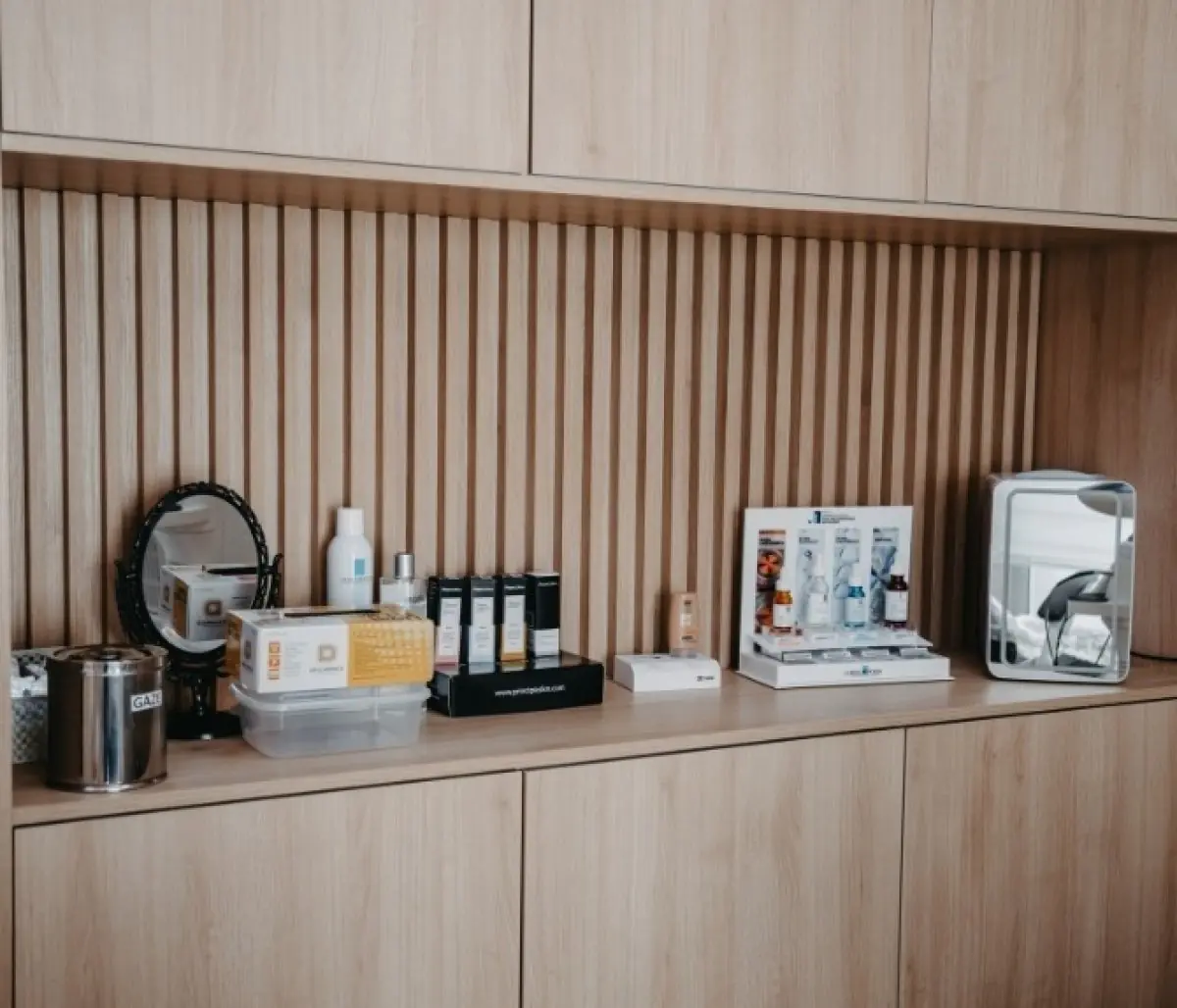 Cosmetic products and mirrors on wooden shelf at Camara Lopes clinic