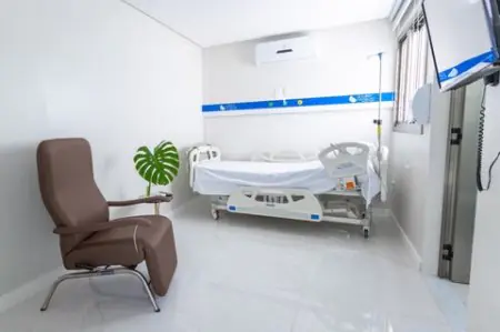 Habitación de paciente en Hospital Dia Glauber Carvalho con cama hospitalaria y sillón