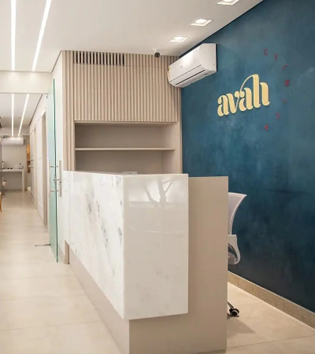Reception area at Avah Clinic with modern marble desk and blue accent wall