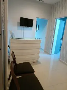 Área de recepción en la clínica Dr. Karaly Castillo con mostrador moderno y TV