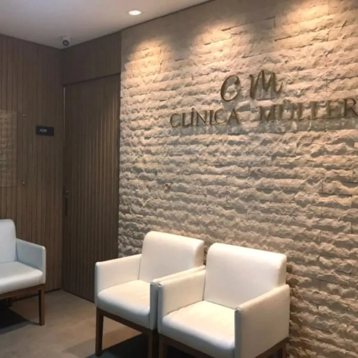 Зона очікування в Clínica Müller із сучасними білими кріслами та фактурною стіною