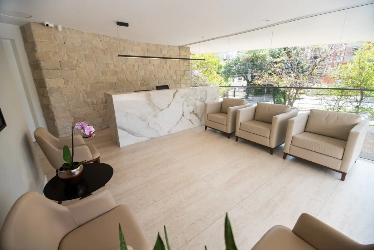 Reception area at Dr. Ricardo Zambenedetti clinic with modern seating and marble desk