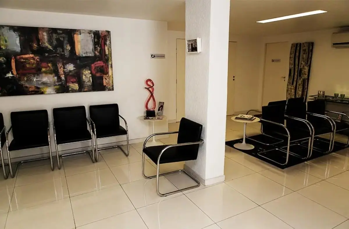 Modern waiting room at Dr. Alexandre Meira clinic with black chairs and abstract art