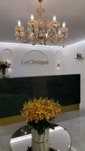 Área de recepción en Le Clinique con lámpara de araña y arreglo floral