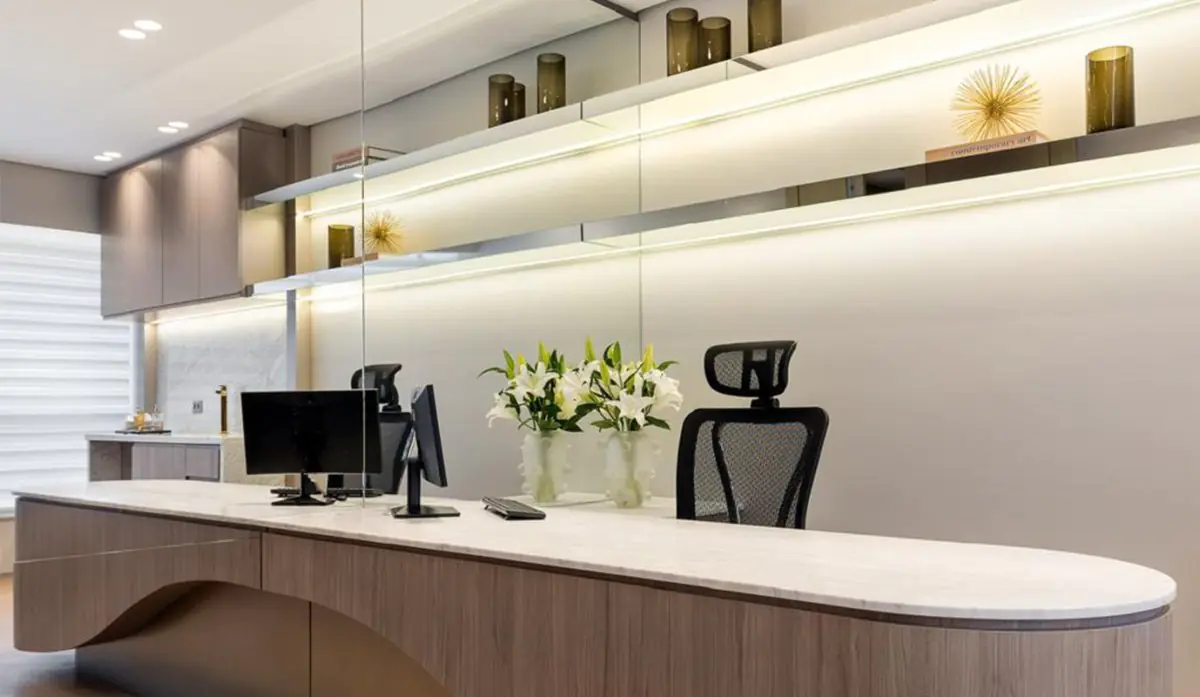 Modern reception desk at Colonetti clinic with computer monitors and flower arrangement