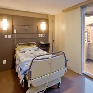 Habitación de paciente en la clínica Colonetti con cama hospitalaria y balcón con vista a la ciudad