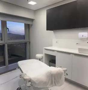 Sala de tratamiento moderna en la clínica Steffen con camilla y vista a la ciudad