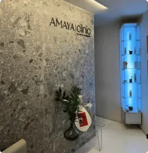 Área de recepción moderna en AmayaClinic® con pared decorativa y vitrina iluminada