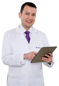 Dr. Raul Daza con bata de clínica usando una tableta, especialista en cirugía plástica