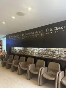 Sala de espera de clínica de cirugía plástica con sillas modernas y pared de piedra
