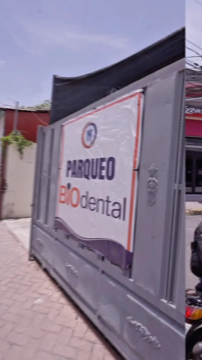 Entrée du parking de la clinique Biodental avec panneau sur portail métallique